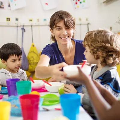 Woman helps children eat