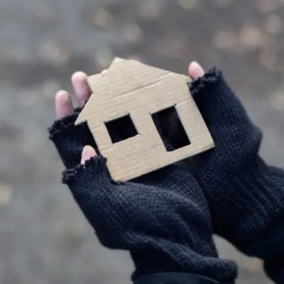 Person wearing gloves holds a cardboard house
